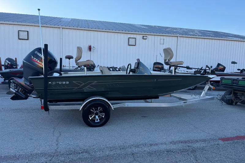 Slide: The Image of 2021 Xpress X18PFC boat on trailer, parked outdoors near a white building. - 32