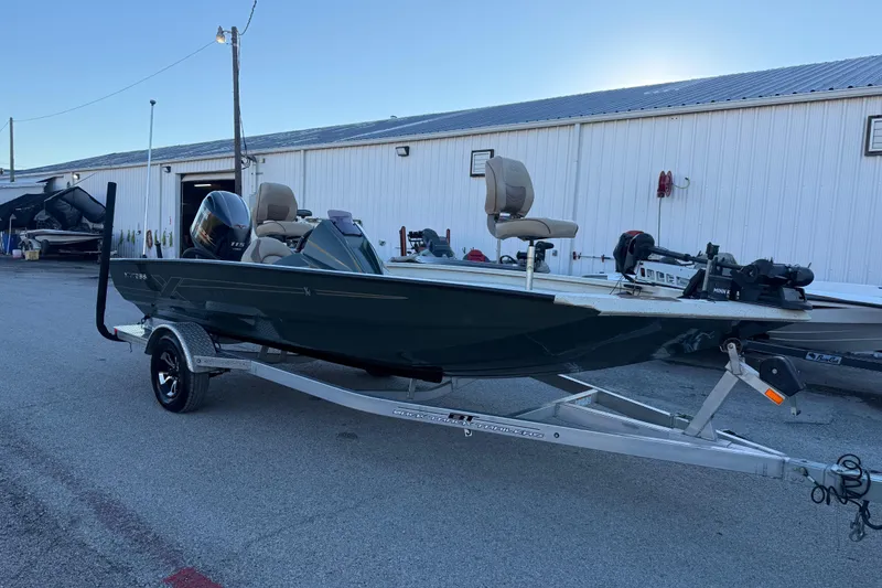 Slide: The Image of 2021 Xpress X18PFC boat on trailer, parked near a white building. - 35