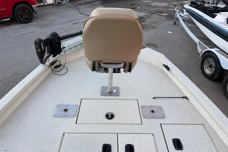 Slide: The Image of 2021 Xpress X18PFC boat deck with beige seat and motor, parked on pavement. - 53