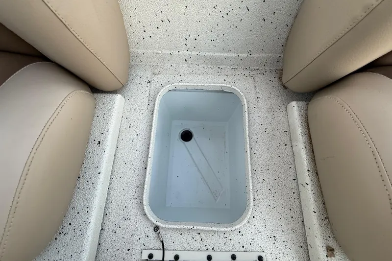 Slide: The Image of 2021 Xpress X18PFC boat interior with storage compartment between beige seats. - 69