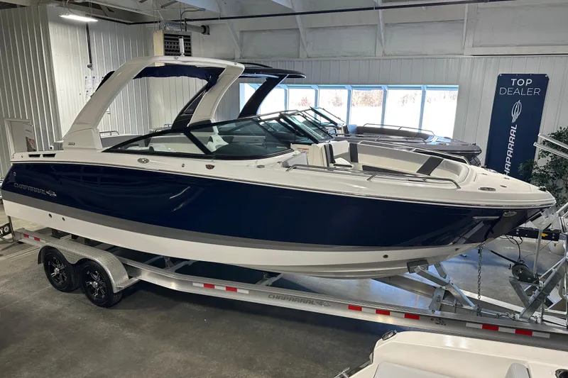 Slide: The Image of 2026 Chaparral SSX 8 boat on trailer in showroom, sleek design, blue and white exterior. - 4