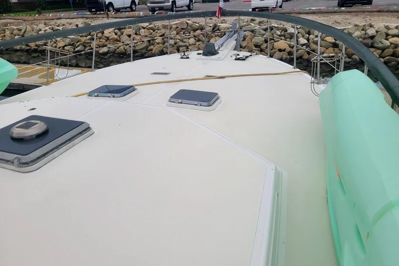 Slide: The Image of 1984 Spindrift 52 Motoryacht deck with hatches and railing, docked near rocky shore. - 5