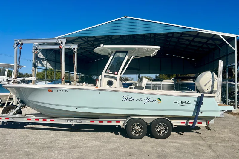 The Image of 2023 Robalo 266 Cayman boat on trailer under metal canopy. - 0