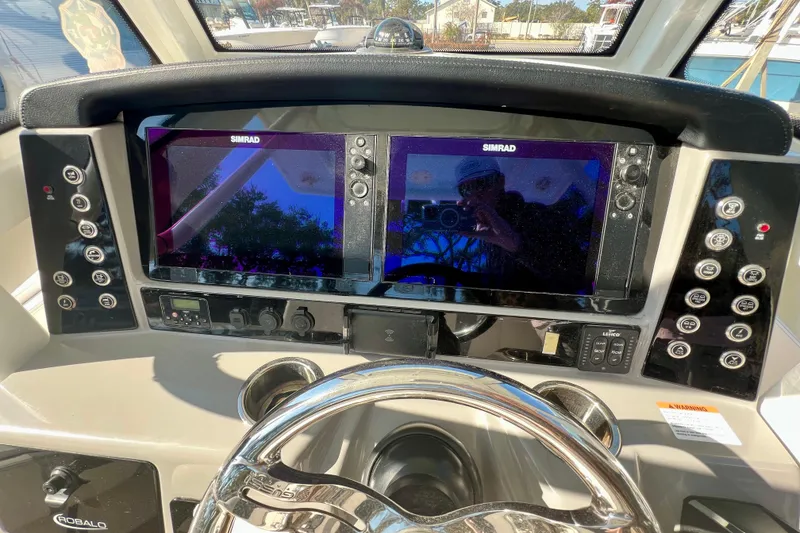 Slide: The Image of 2023 Robalo 266 Cayman boat dashboard with dual Simrad displays and control panels. - 11