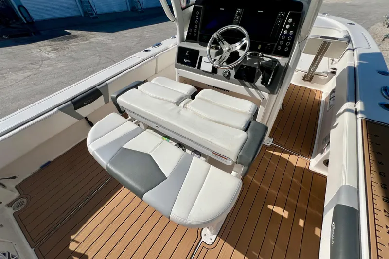 Slide: The Image of 2023 Robalo 266 Cayman boat interior with helm and seating, featuring teak flooring. - 17