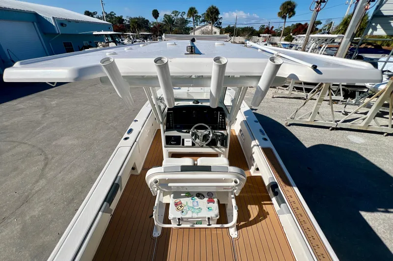 Slide: The Image of 2023 Robalo 266 Cayman boat interior with helm and rod holders, docked outdoors. - 19