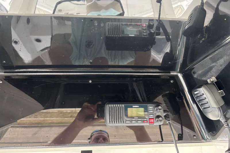 Slide: The Image of 2023 Yamaha Boats 222 FSH Sport dashboard with Uniden radio and microphone. - 16