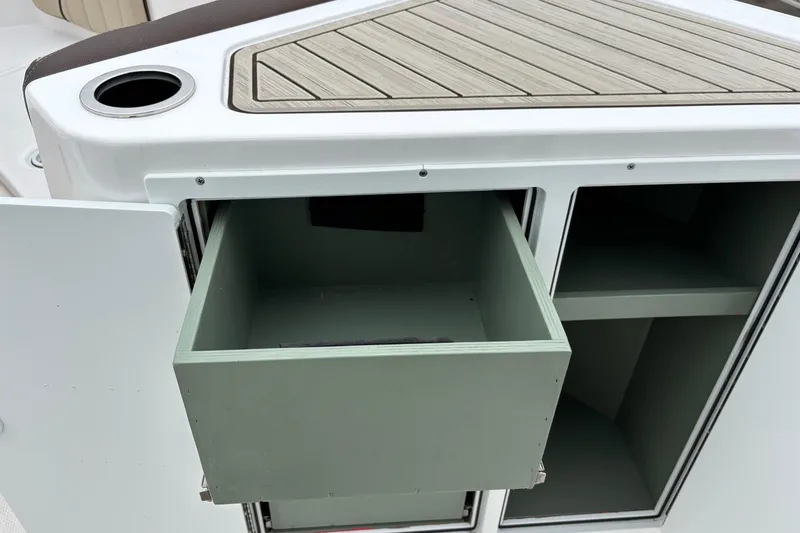 Slide: The Image of 2023 Yamaha Boats 222 FSH Sport storage compartment with open drawer and cup holder. - 4