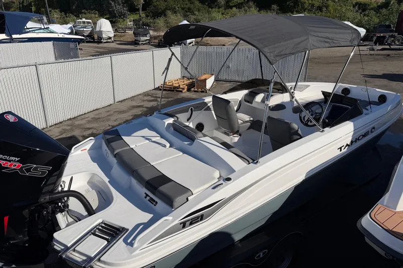 Slide: The Image of 2024 Tahoe T21 boat with canopy, docked in a marina, featuring sleek design and comfortable seating. - 2