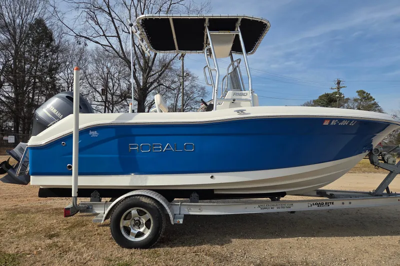 The Image of 2017 Robalo R180 Center Console boat on trailer, blue and white design, Yamaha engine. - 0
