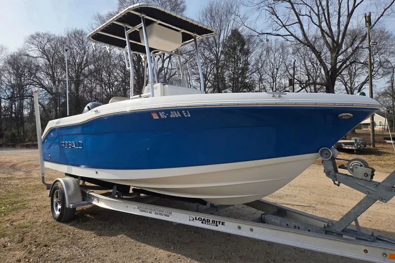 Slide: The Image of 2017 Robalo R180 Center Console boat on trailer, blue hull, parked outdoors. - 3
