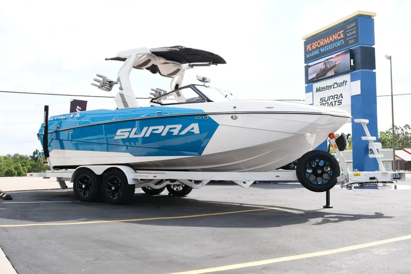 Slide: The Image of 2026 Supra SL boat on trailer at dealership, featuring sleek blue and white design. - 9