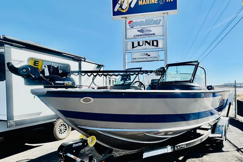 Slide: The Image of 2026 Lund 2075 Fisherman boat displayed at a dealership under clear blue skies. - 1