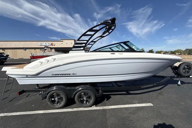 Slide: The Image of 2025 Chaparral 23 SSi boat on trailer, parked in a lot under a clear blue sky. - 6