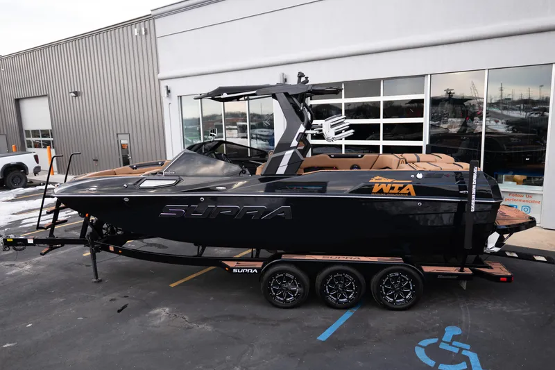 Slide: The Image of 2024 Supra SE boat in black, parked on a trailer outside a building. - 4