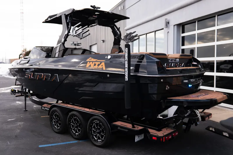 Slide: The Image of 2024 Supra SE boat on trailer, sleek black design, parked outside a garage. - 5