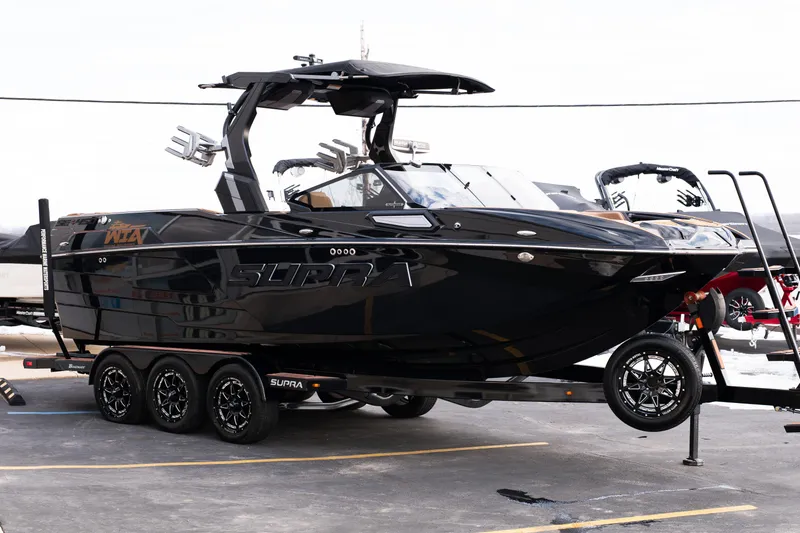 Slide: The Image of 2024 Supra SE boat in sleek black finish on a trailer, showcasing modern design. - 57