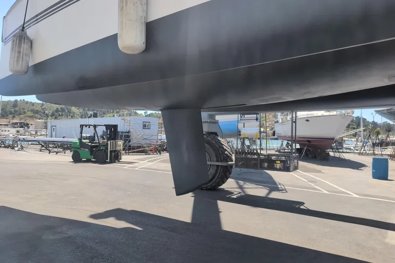 Slide: The Image of A 2016 Dragonfly 32 sailboat on land, with visible keel and nearby forklift. - 4