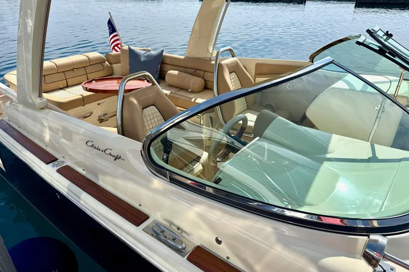 Slide: The Image of 2019 Chris-Craft Launch 28 GT boat with elegant seating and American flag on calm water. - 11