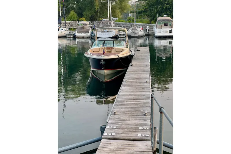 Slide: The Image of 2019 Chris-Craft Launch 28 GT docked at a marina, surrounded by other boats. - 12