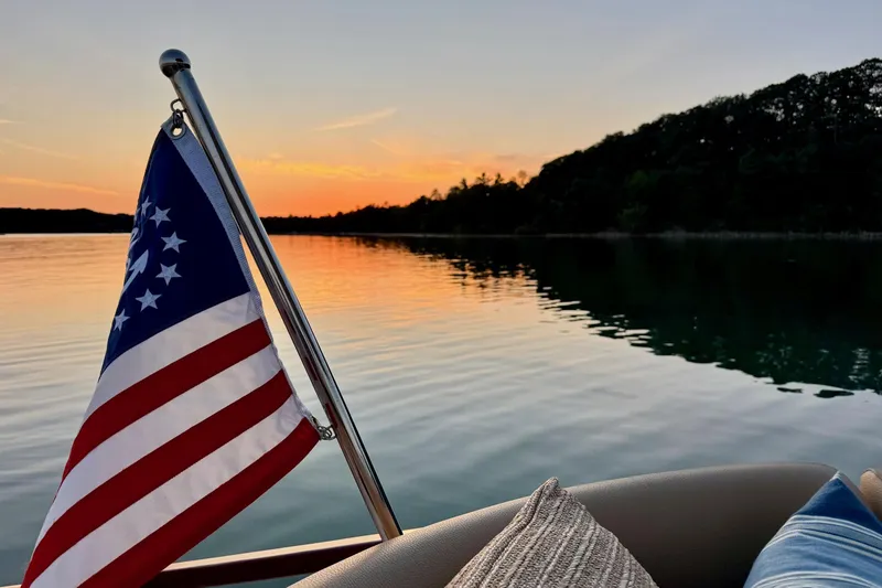 Slide: The Image of 2019 Chris-Craft Launch 28 GT at sunset, American flag waving on calm lake. - 9