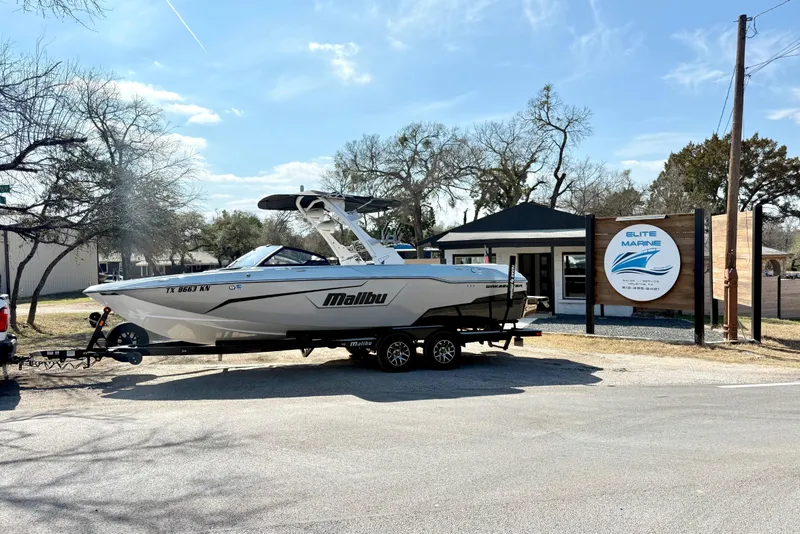 The Image of 2021 Malibu Wakesetter 25 LSV boat on trailer outside Elite Marine shop. - 1