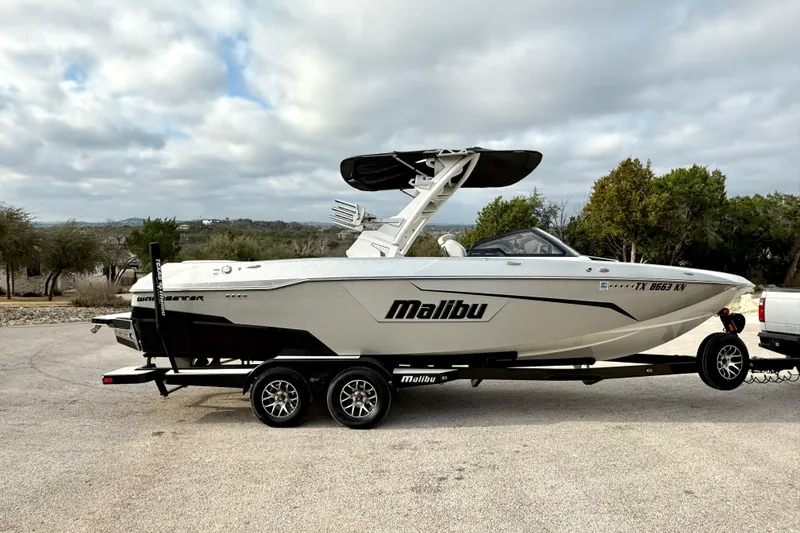 Slide: The Image of 2021 Malibu Wakesetter 25 LSV boat on trailer, parked outdoors under cloudy sky. - 10