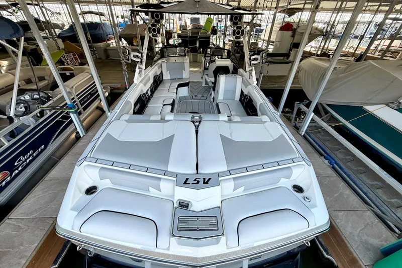 Slide: The Image of 2021 Malibu Wakesetter 25 LSV boat docked in a marina, showcasing sleek design and spacious seating. - 15