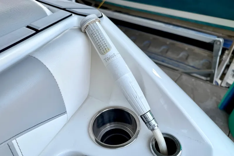 Slide: The Image of 2021 Malibu Wakesetter 25 LSV boat interior with a white hose and cup holder. - 32