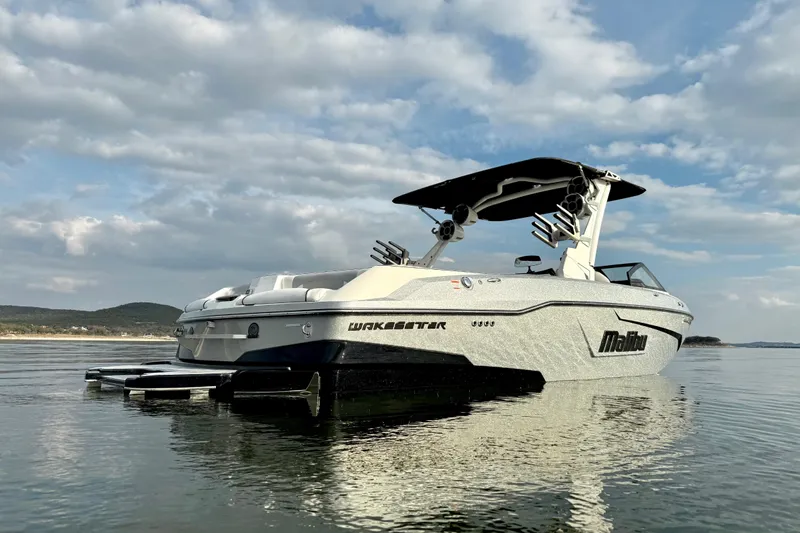 Slide: The Image of 2021 Malibu Wakesetter 25 LSV boat on calm water under a cloudy sky. - 5