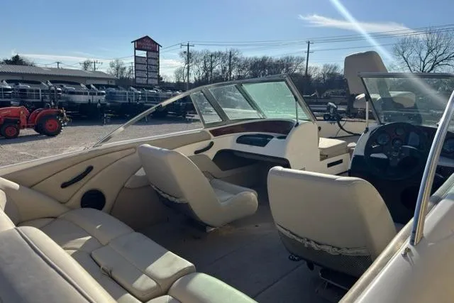 Slide: The Image of 2002 Triton SF-21 boat interior with beige seating and dashboard, parked outdoors. - 3
