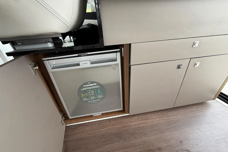 Slide: The Image of Interior of 2020 Beneteau Antares 9 showing a Dometic fridge and storage cabinets. - 22