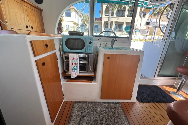 Slide: The Image of Interior of 2000 Lagoon 380 catamaran with kitchenette, featuring wood cabinets and retro appliances. - 11