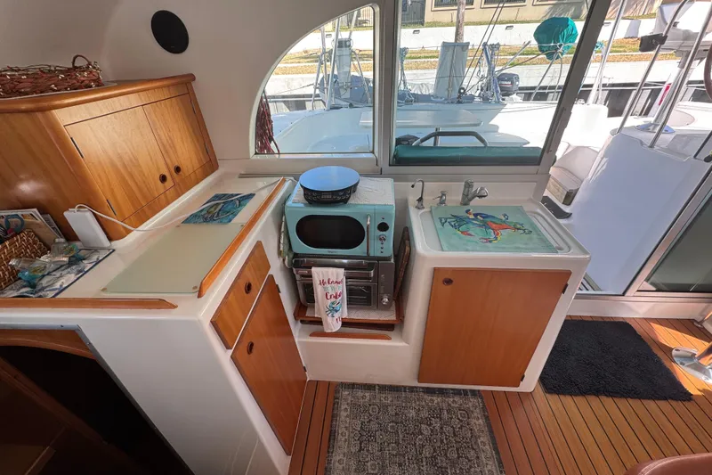 Slide: The Image of Interior of 2000 Lagoon 380 catamaran kitchen with wooden cabinets and modern appliances. - 12