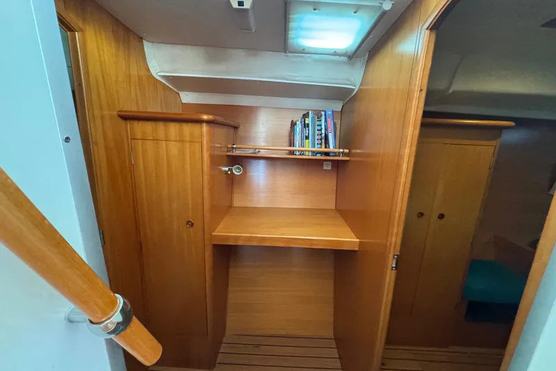 Slide: The Image of Interior of 2000 Lagoon 380 catamaran with wooden cabinetry and books on a shelf. - 14