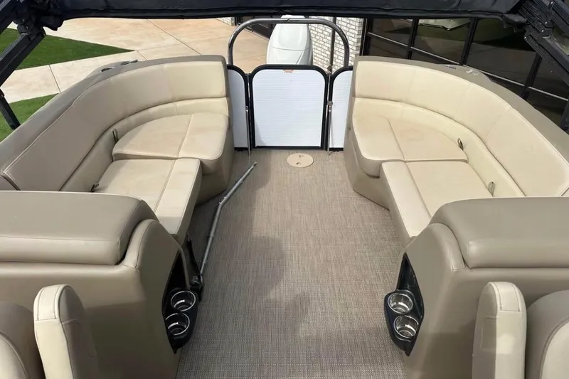 Slide: The Image of 2022 Manitou 25 AURORA LE RF pontoon boat interior with beige seating and cup holders. - 3
