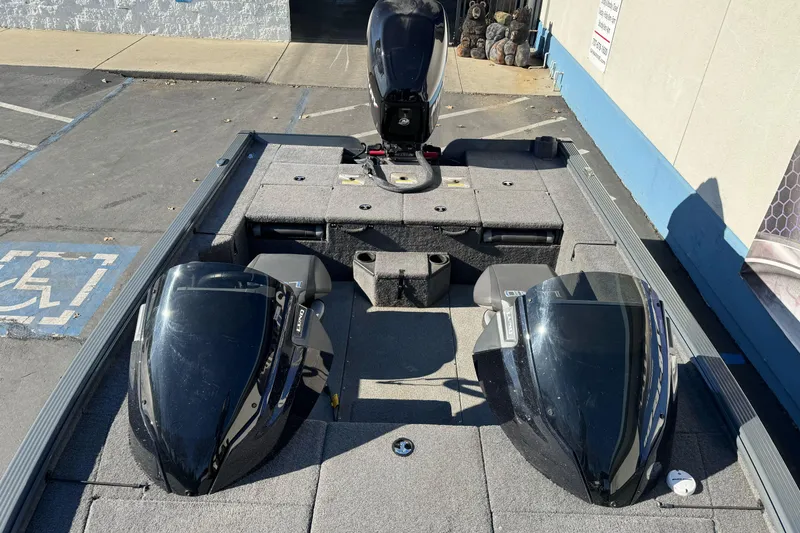 Slide: The Image of 2018 Lund 1875 Pro-V Bass boat with dual consoles and outboard motor in a parking lot. - 13