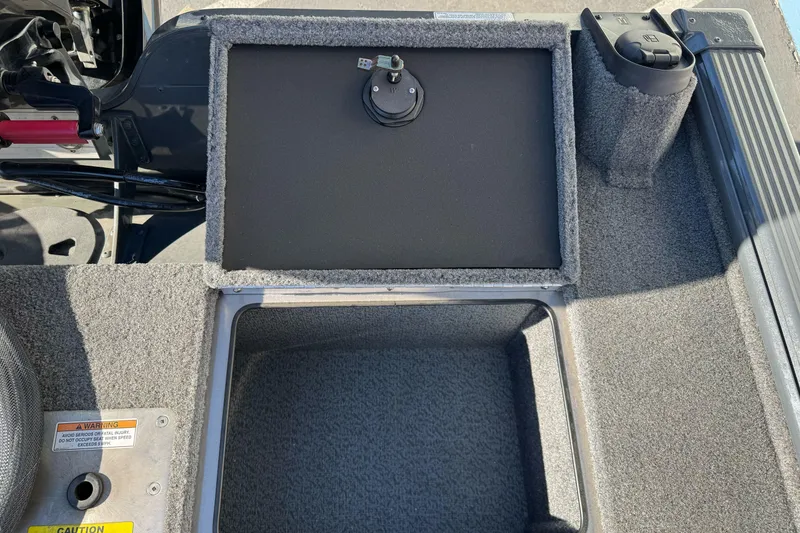 Slide: The Image of 2018 Lund 1875 Pro-V Bass boat storage compartment with carpeted interior and warning label. - 23