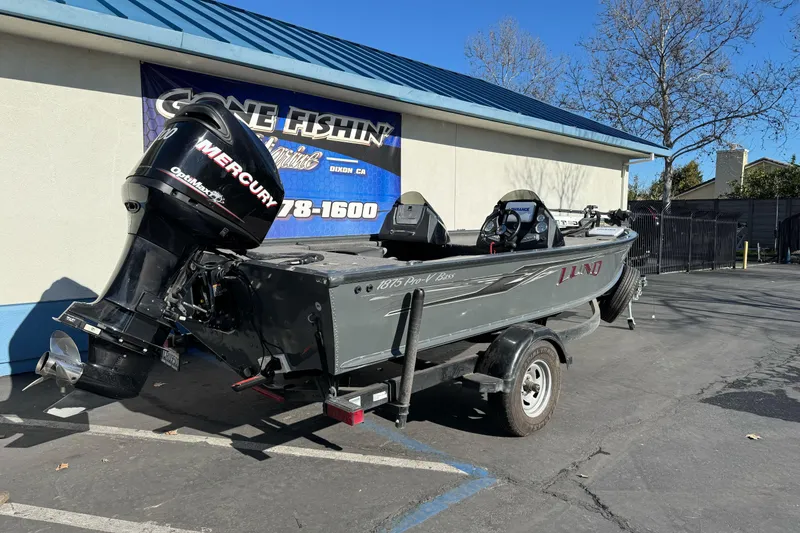 Slide: The Image of 2018 Lund 1875 Pro-V Bass boat with Mercury engine on trailer, parked outside. - 4