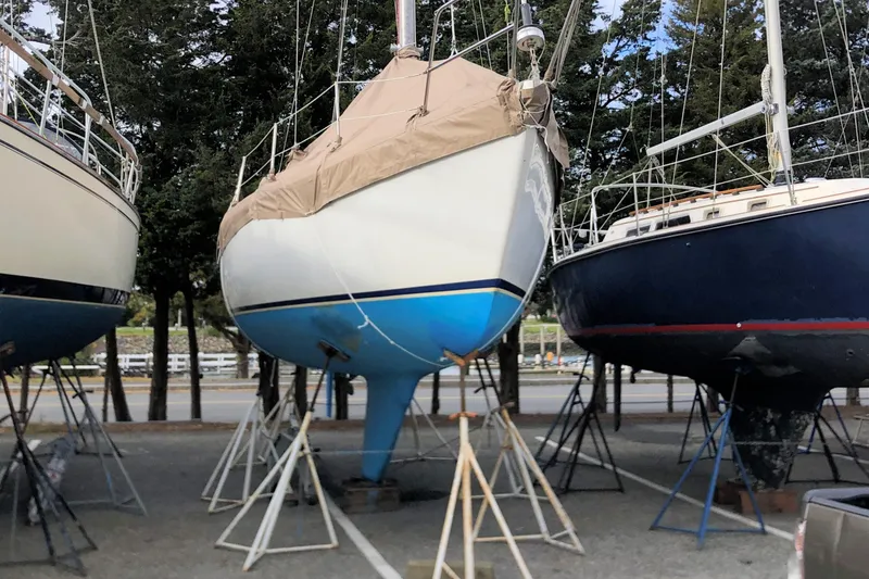 Slide: The Image of 1981 Catalina 30 sailboat on stands, covered, in a boatyard setting. - 14