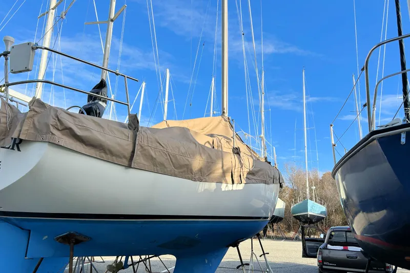 Slide: The Image of 1981 Catalina 30 sailboat on land, covered, with clear blue sky background. - 15