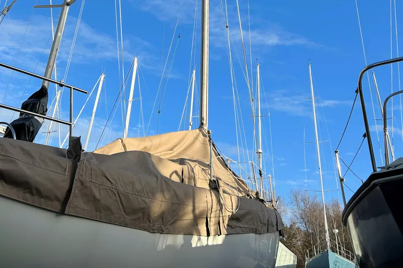 Slide: The Image of 1981 Catalina 30 sailboat with covered deck, surrounded by other masts, under clear blue sky. - 16