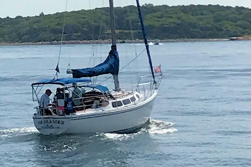Slide: The Image of 1981 Catalina 30 sailboat cruising on calm waters near a forested shoreline. - 6