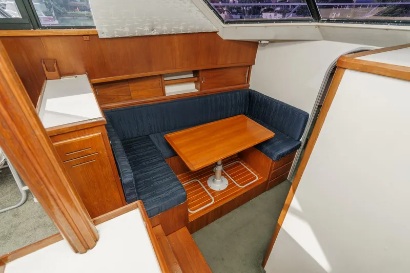 Slide: The Image of 1989 Pearson 34 Convertible yacht interior with wooden dining area and blue seating. - 13