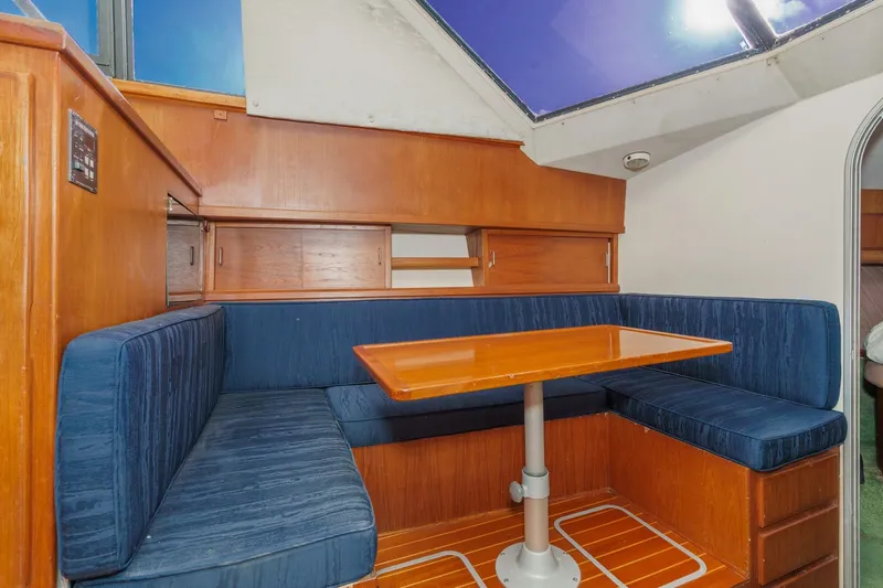 Slide: The Image of 1989 Pearson 34 Convertible yacht interior with blue seating and wooden table. - 14