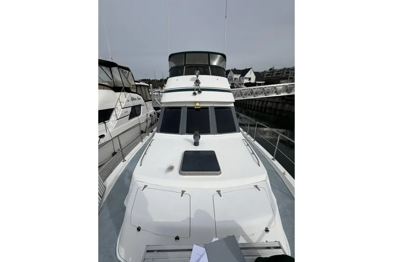 Slide: The Image of 1984 Gulfstar 49 Motor Yacht docked at marina, showcasing sleek design and spacious deck. - 22