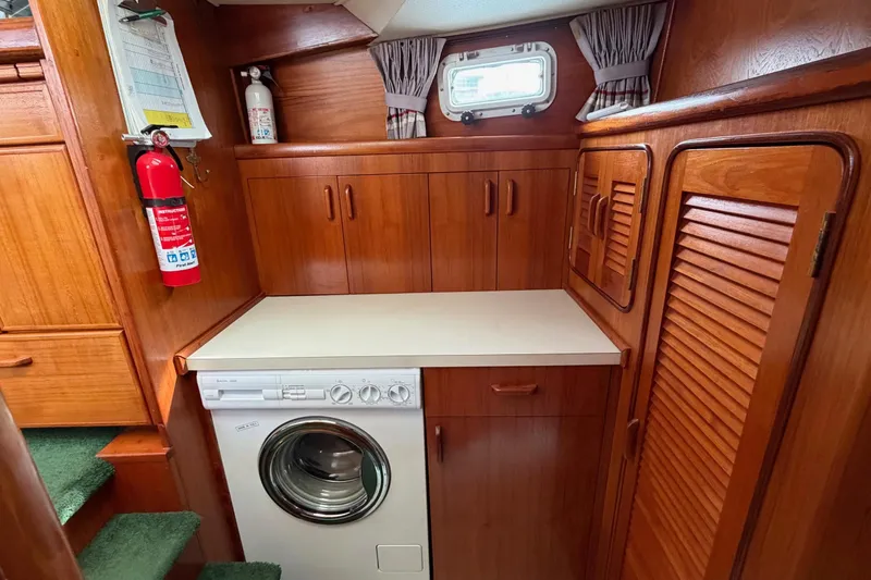 Slide: The Image of Laundry area in 1984 Gulfstar 49 Motor Yacht with washer, wooden cabinets, and fire extinguisher. - 47