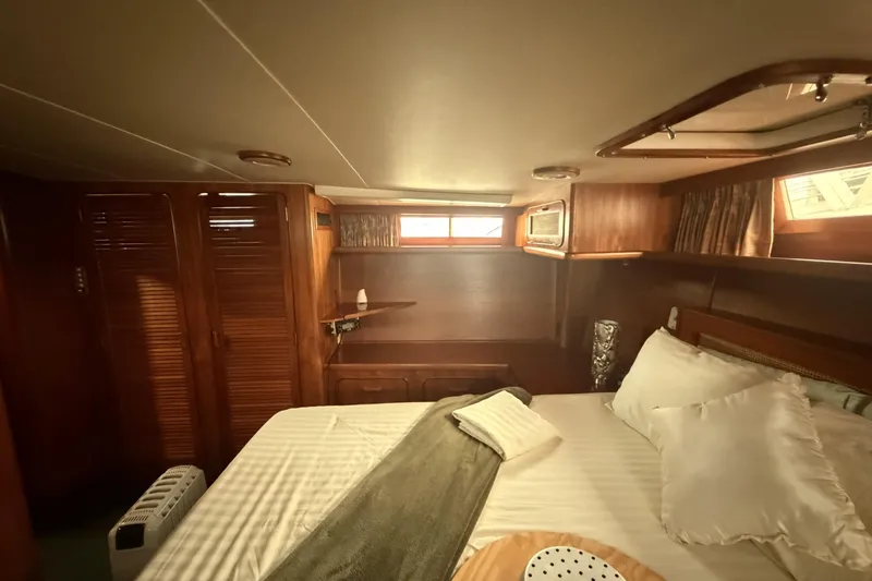 Slide: The Image of Cozy bedroom interior of 1984 Gulfstar 49 Motor Yacht with wood paneling and plush bedding. - 65