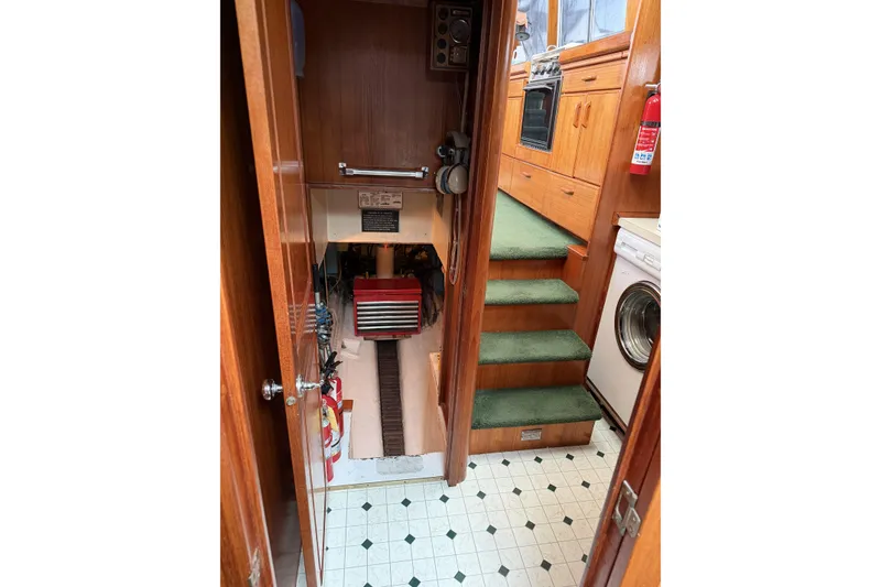 Slide: The Image of Interior of 1984 Gulfstar 49 Motor Yacht with green carpeted stairs and wooden cabinetry. - 73