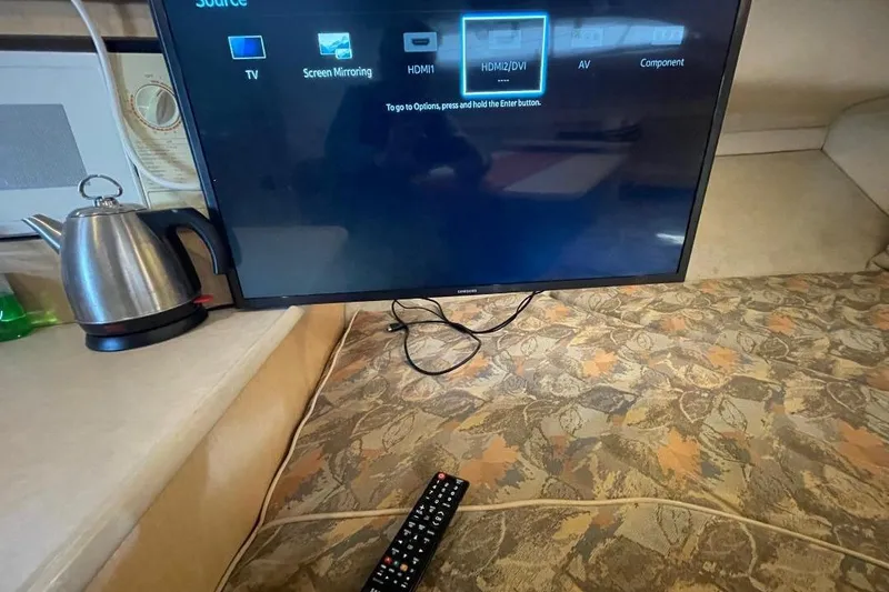 Slide: The Image of TV setup inside 2000 Bayliner 2655 Ciera Sunbridge, with remote and kettle nearby. - 10